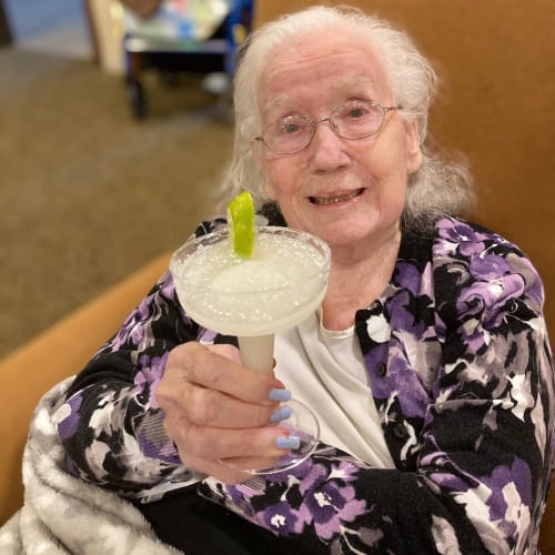 Resident holding a margarita at Oxford Glen Memory Care at Carrollton in Carrollton, Texas