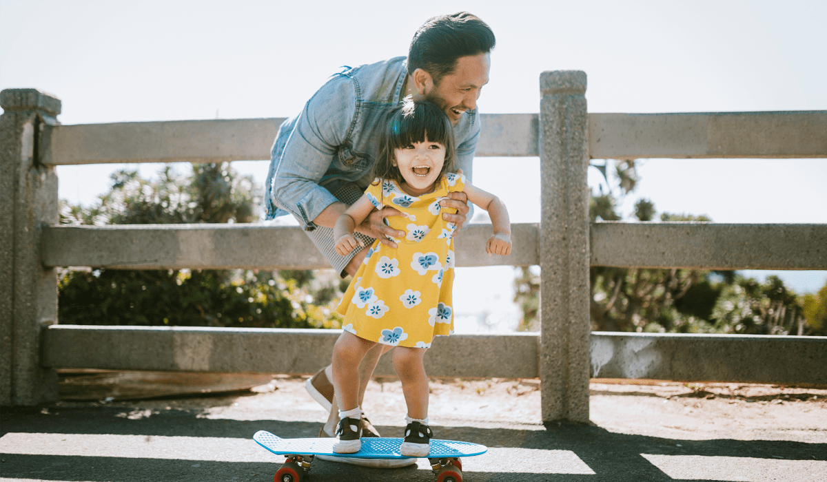 Father and daughter playing with a skateboard near Windward Apartments in Orlando, Florida