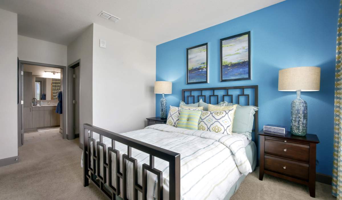 Master bedroom with king size bed, side table lamp, carpet flooring and access to bathroom at The Addison on Millenia in Orlando, Florida