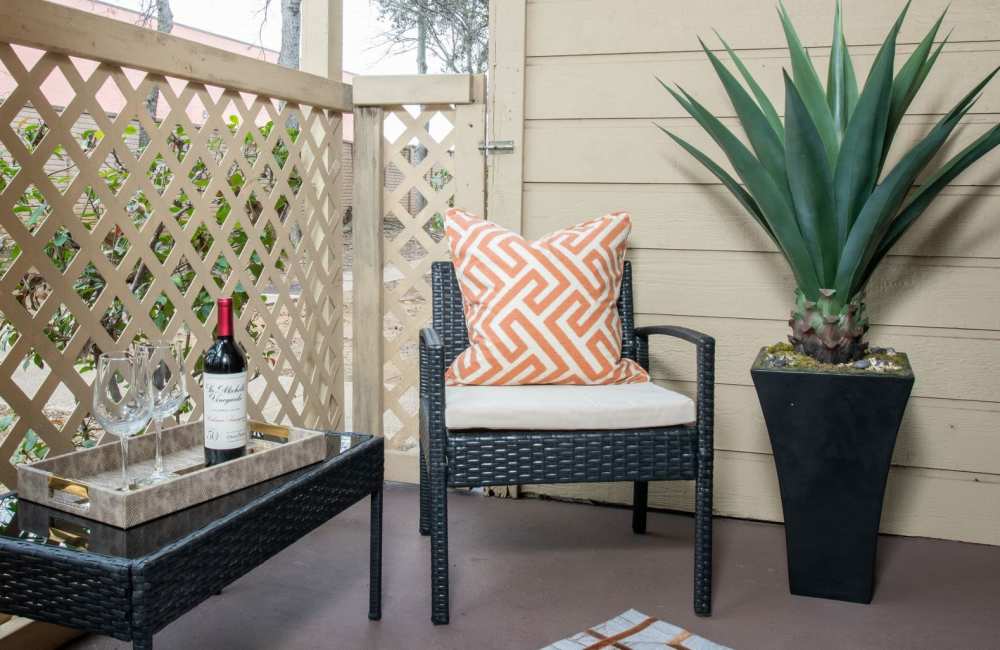 Charming balcony retreat at Charter Oak in Euless, Texas, featuring cozy seating, stylish decor, and lush greenery.
