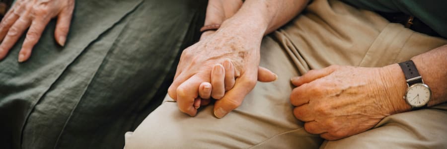 Resident couple sitting together holding hands at a WISH community