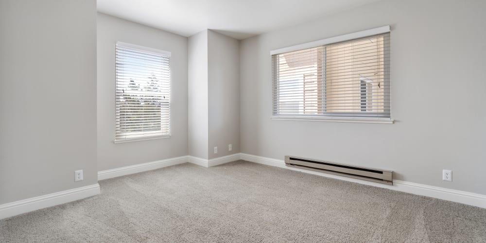 Carpeted bedroom with large windows at Quail Hill Apartments in Castro Valley, California