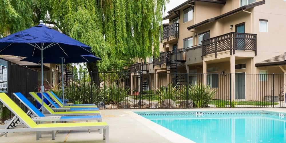 Swimming pool and lounge chairs with umbrella at Octave in Davis, California