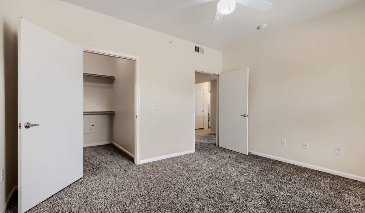 Spacious bedroom with carpeted flooring, ceiling fan, and open closet space at Lindbergh Parc Senior Apartments in Fort Worth, Texas