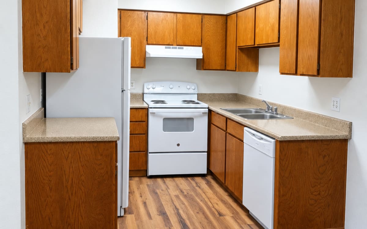 Apartment kitchen with wood cabinetry at Pleasant Run Apartments in Lancaster, Texas
