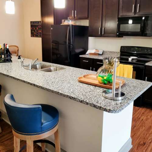 Apartment kitchen with granite countertops and black appliances at Waterside in Graham, North Carolina