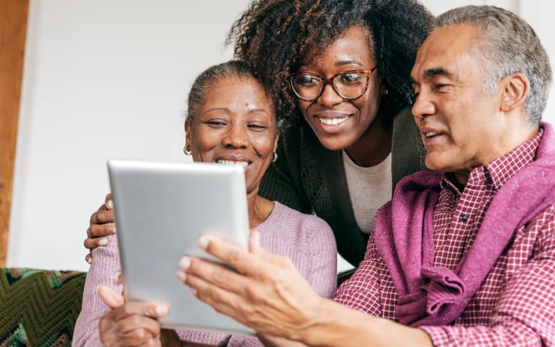 Resident couple using a tablet computer with help from a younger family member at Blossom Springs in Oakland Twp, Michigan