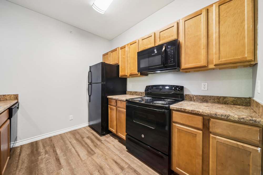Modern kitchen with black appliances and wood flooring at Village at Carlsbad in Carlsbad, New Mexico