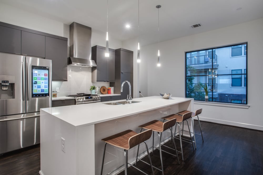 Apartment kitchen with marble countertops and stainless steel fridge at The Collection Townhomes in Dallas, Texas