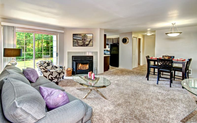 Spacious living room with plush carpeting and a fireplace at Wellington Apartment Homes in Silverdale, Washington