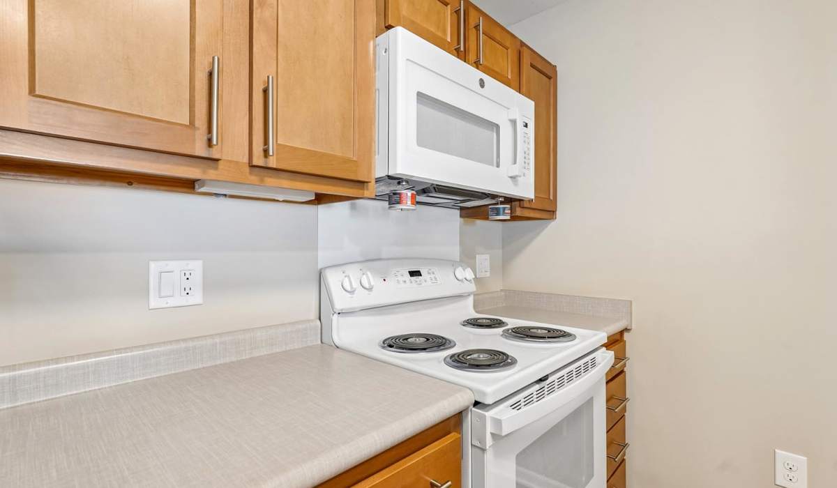 Modern kitchen with wooden cabinets, white appliances, and ample countertop space at Juniper Crossing I in Columbus, Ohio