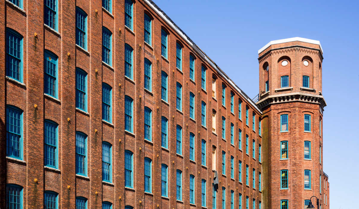 Garden style brick wall with blue windows and tower at Commonwealth Landing Lofts in Fall River, Massachusetts