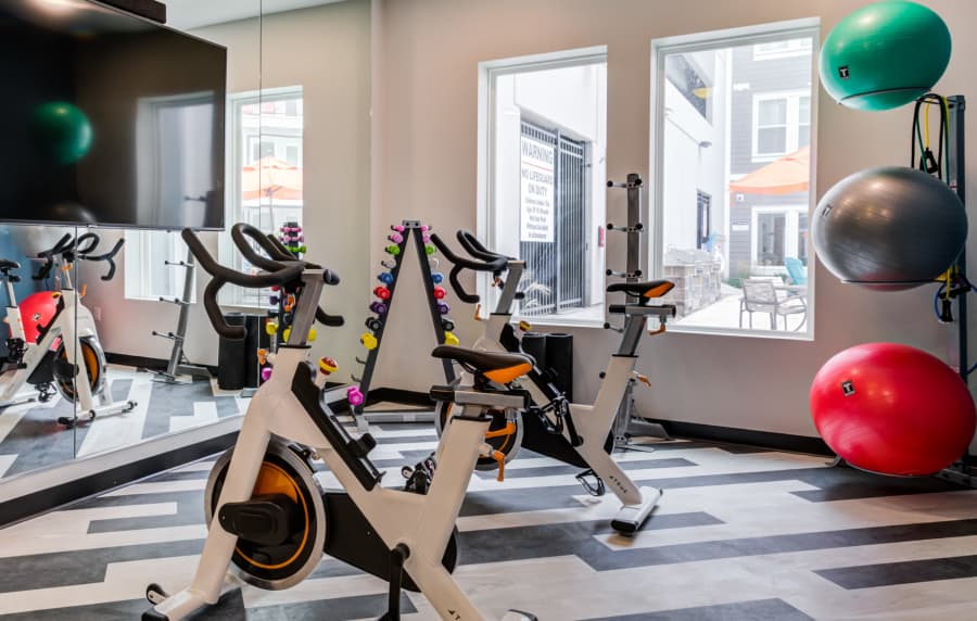 Community fitness center with cycling, exercise ball and television at Altair At The Heights in Richmond Heights, Missouri