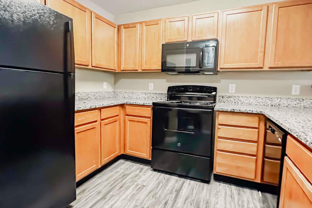 Fully-equipped kitchen with black appliances and wooden cabinets at Cushendall Commons in Rock Hill, South Carolina