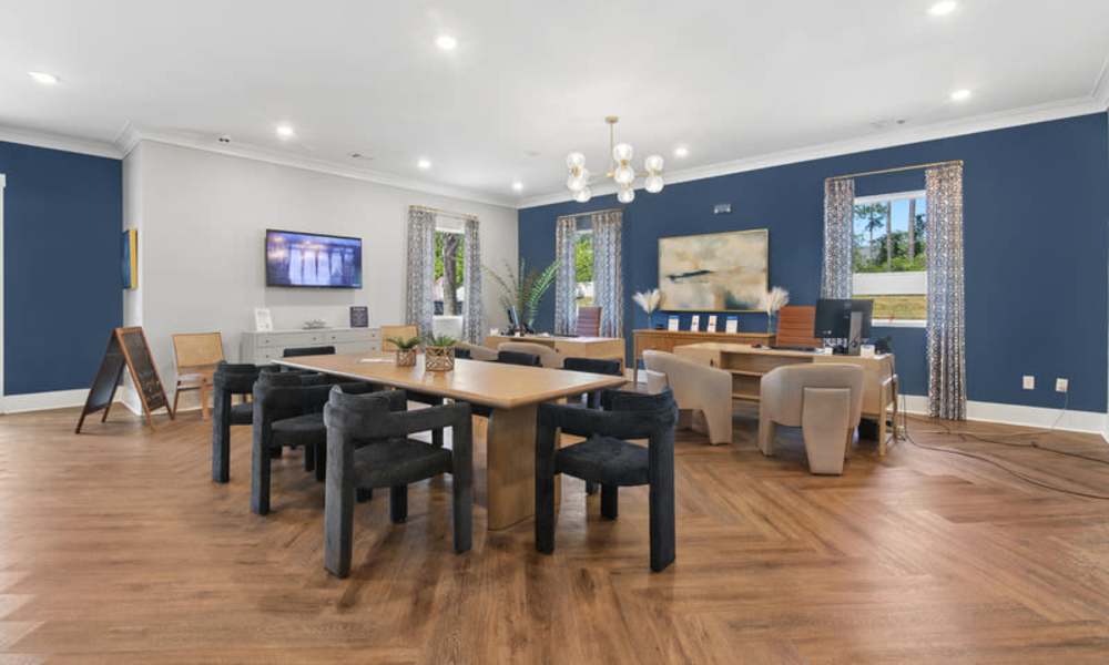 Modern community lounge with wood-style flooring, large windows, and stylish seating arrangements at Everett at Port Wentworth in Port Wentworth, Georgia