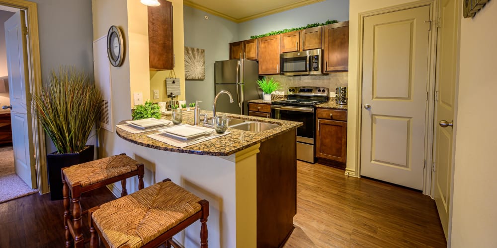 Open concept layout with bar stools and hardwood floors at Pecan Springs Apartments in San Antonio, Texas