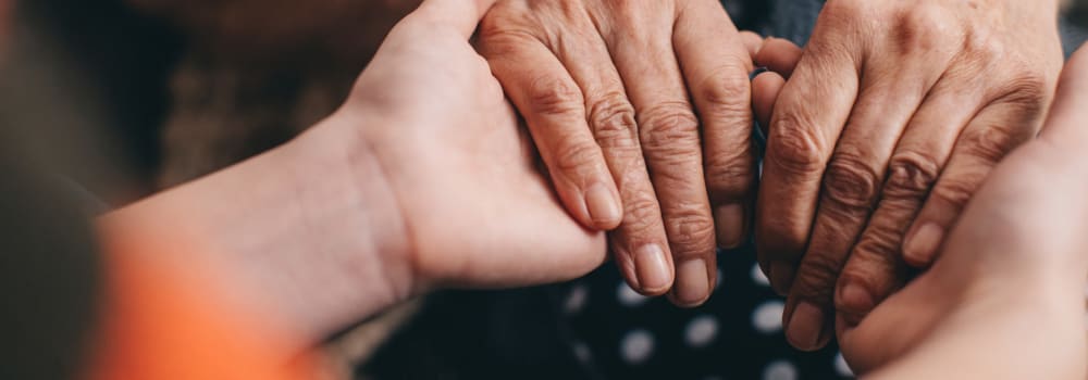 A caring staff member holding a residents hands at a Stoney Brook community. 