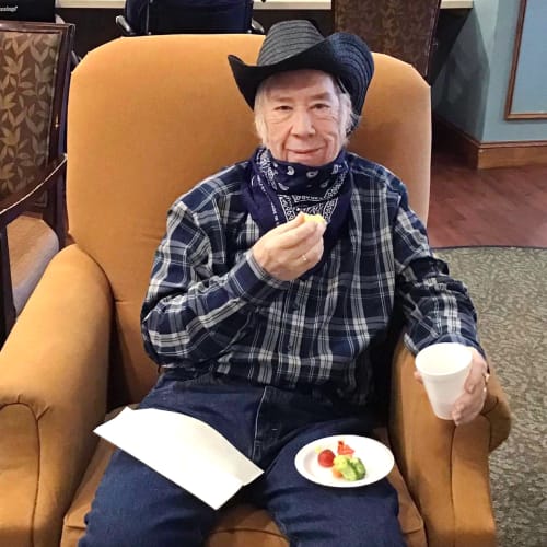 Resident dressed like a cowboy eating in a lounge at Oxford Glen Memory Care at Grand Prairie in Grand Prairie, Texas