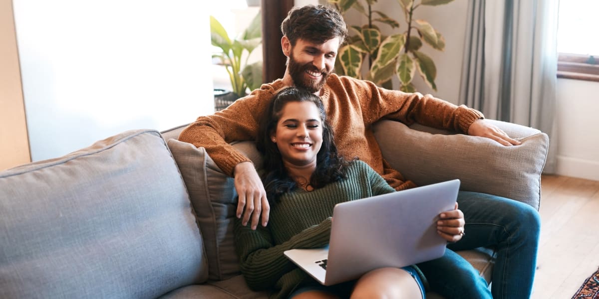 A couple sitting on a couch in an apartment at One90 Main in Rowlett, Texas