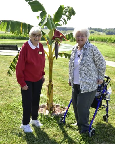 Residents out on a walk taking a picture with a tall plant at Garden Place Columbia in Columbia, Illinois.