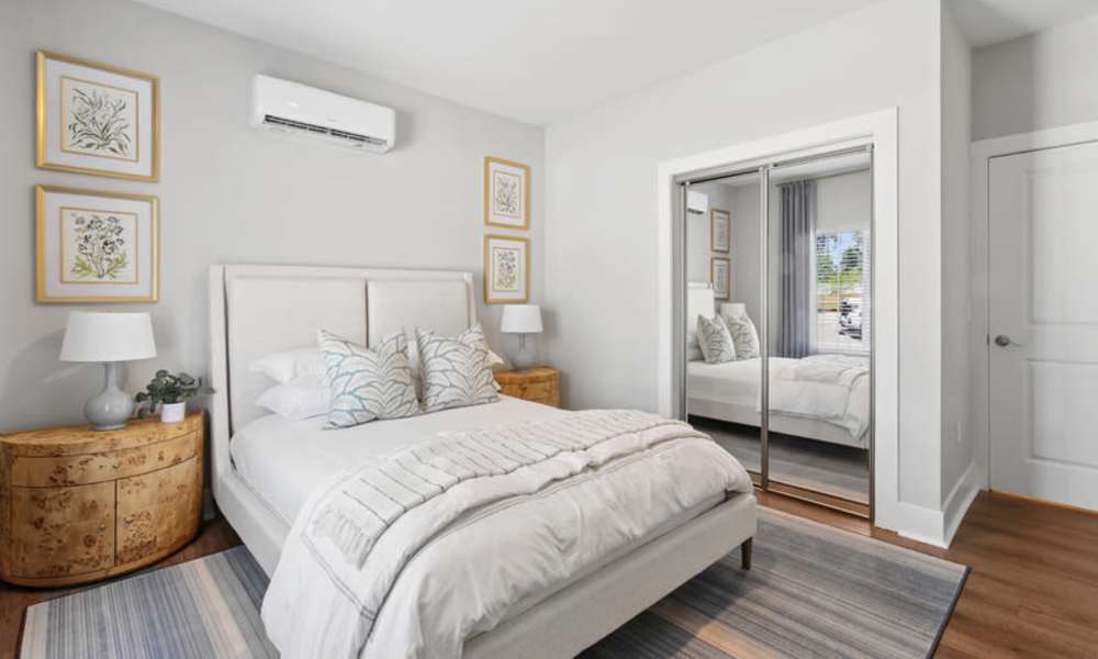 Cozy bedroom with a queen bed, decorative pillows, and wood-style flooring at Everett at Port Wentworth in Port Wentworth, Georgia