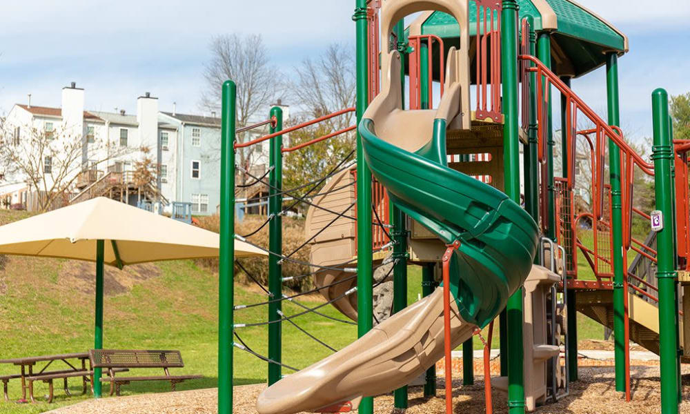 A playground with a large grass lawn at Greenhills Apartments & Townhomes in Damascus, Maryland