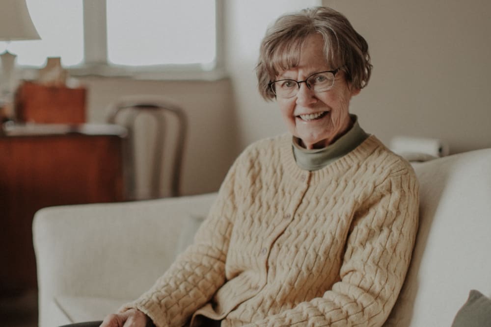 Resident smiling on a couch at The Whitcomb Senior Living Tower in St. Joseph, Michigan