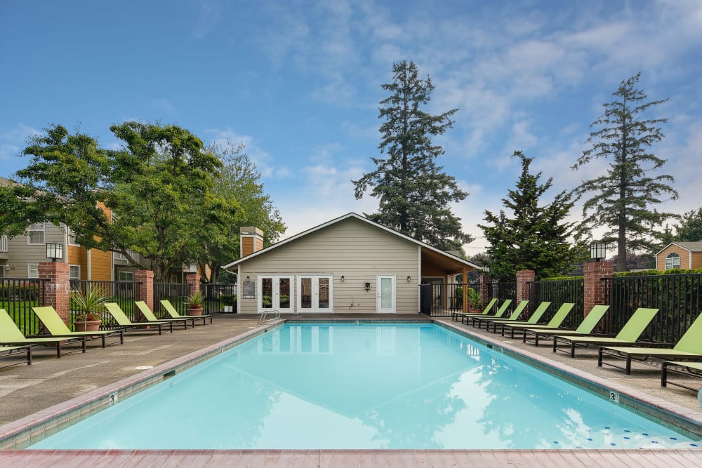 Beautiful resort-style swimming pool with a lush backdrop at Carriage Park Apartments in Vancouver, Washington