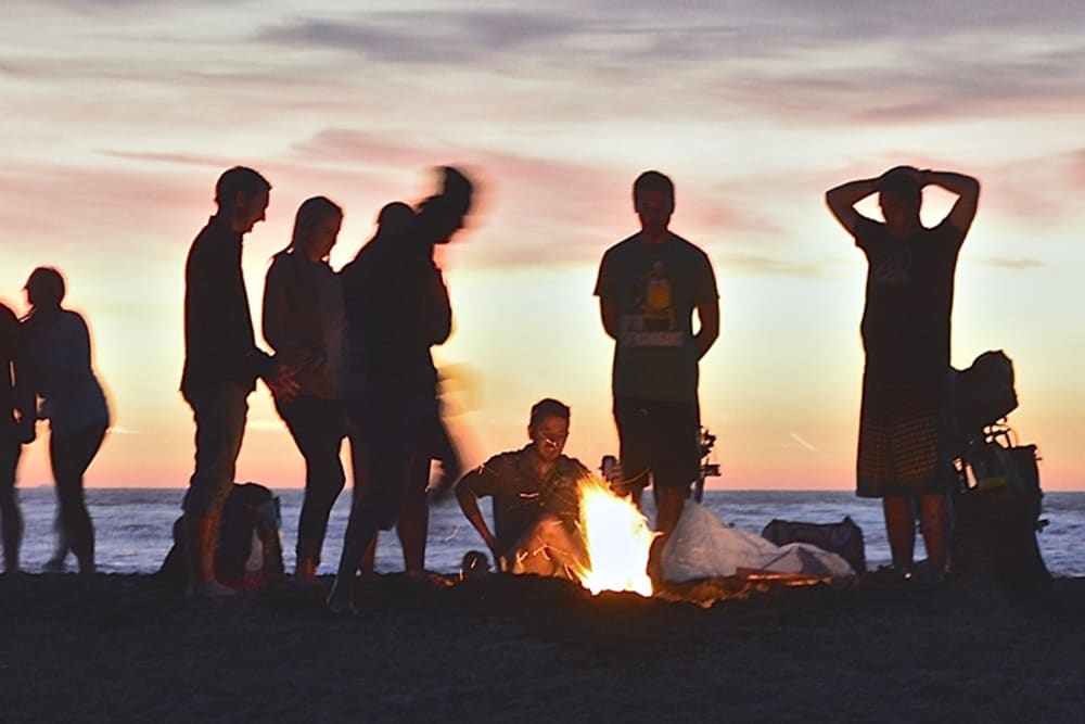 Friends and neighbors enjoying a bonfire on the beach near Pacific Shores apartments