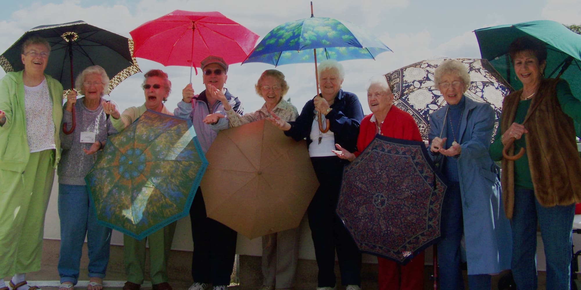 Residents from Hawthorn Senior Living in Vancouver, Washington with umbrellas, enjoying the weather