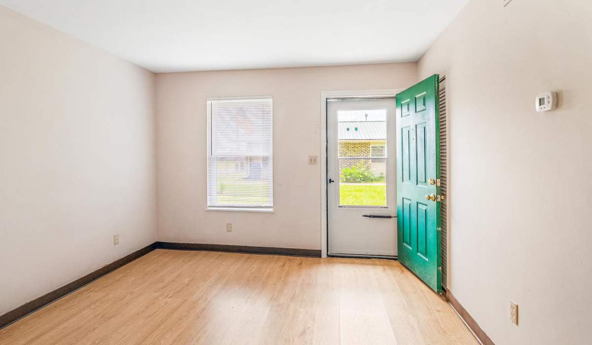 Bright entryway with wood-style flooring and green front door leading to outdoor space at Walnut Street Apartments in Dickson, Tennessee