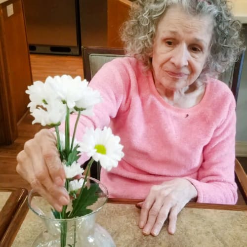 Resident placing some flowers in a vase at Glen Carr House Memory Care in Derby, Kansas