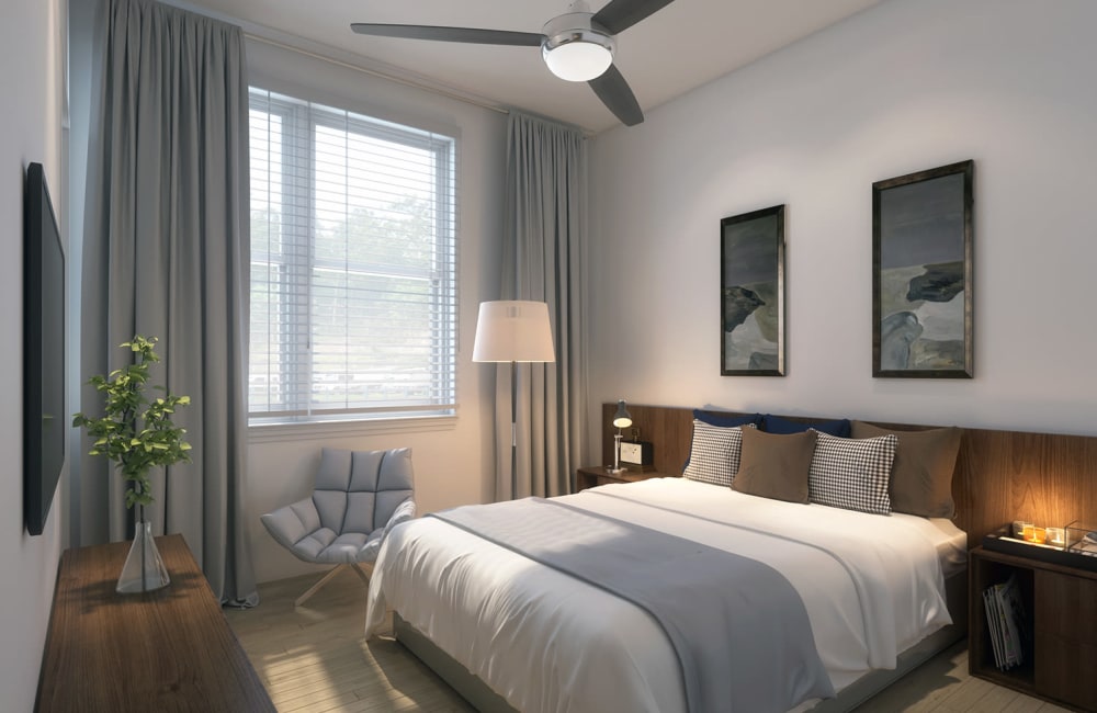 A bright bedroom with a ceiling fan at The Flats at East Bay in Fairhope, Alabama