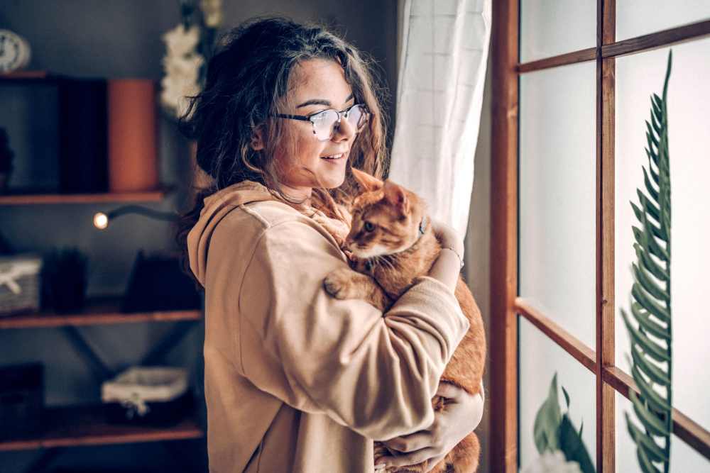 Young woman and her orange tabby in their apartment at The Avenue at 3060 in Atlanta, Georgia