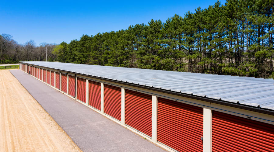 Storage units with red doors and a row of trees behind them at KO Storage in Wisconsin Dells, Wisconsin