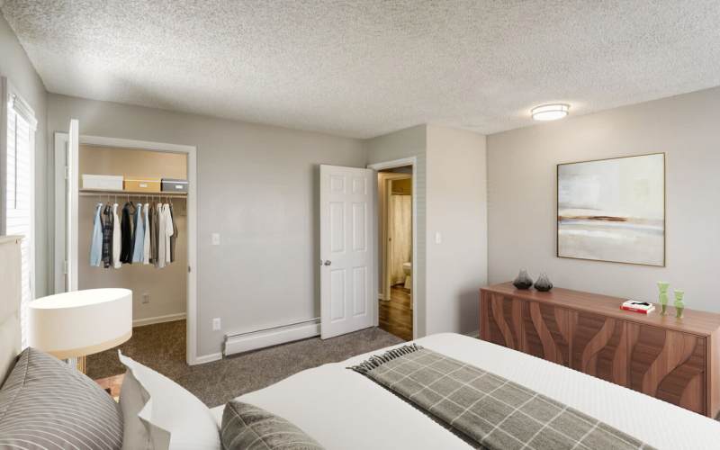 A furnished bedroom with the closet doors open at Ascent at Lowry in Denver, Colorado