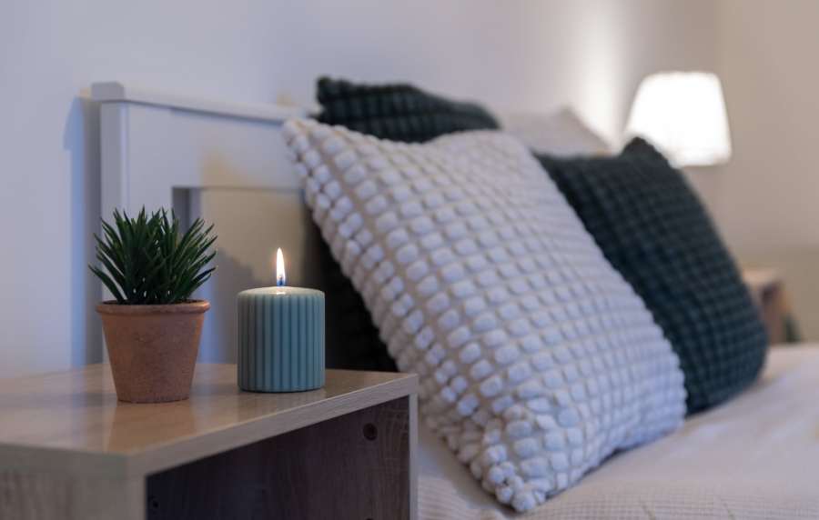 Cozy bedroom with decorative pillows and candle at Jefferson Manor Townhomes in Fairport, New York