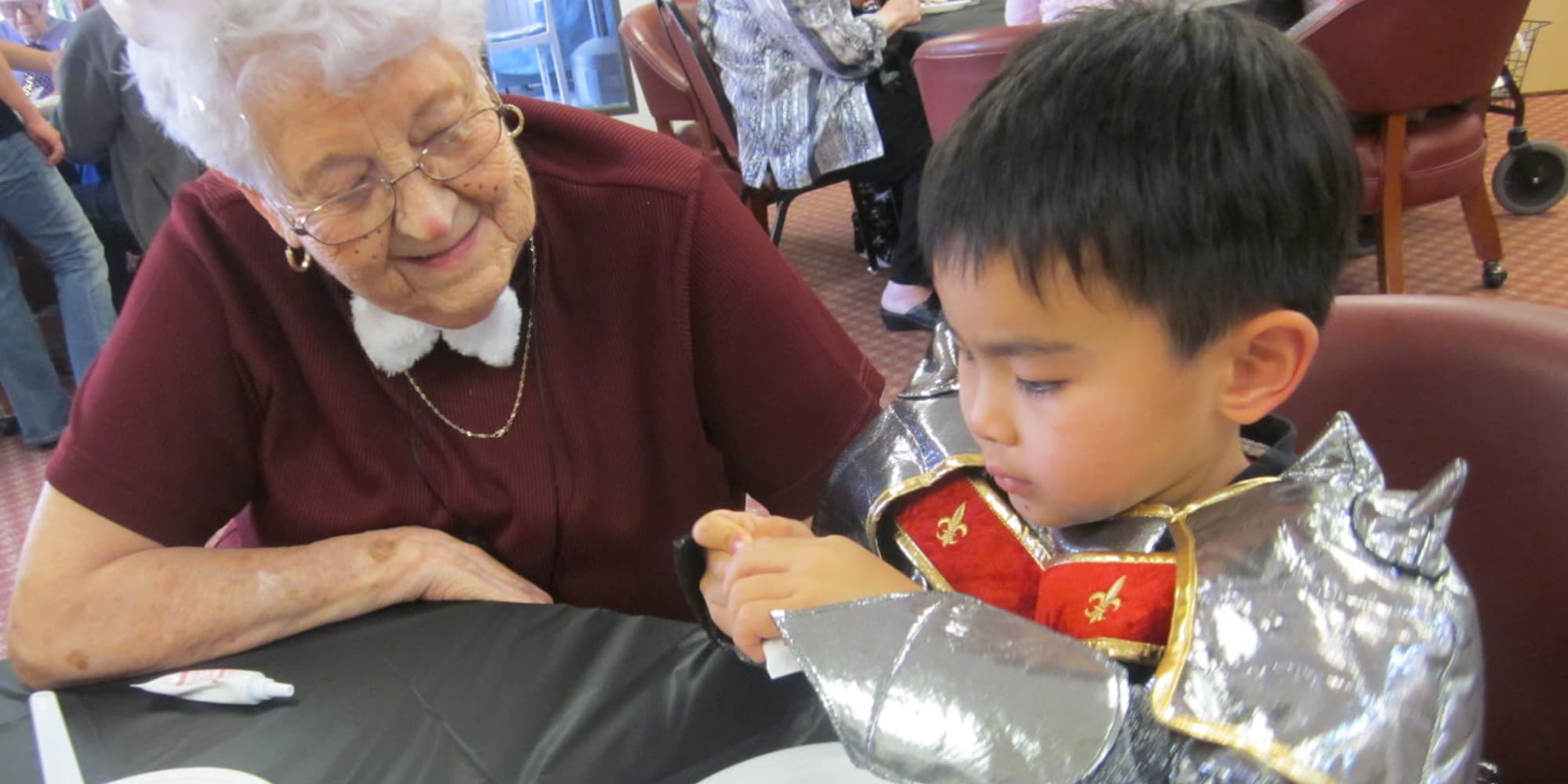 A resident decorating cookies with a child at Victoria Park Personal Care Home in Regina, Saskatchewan
