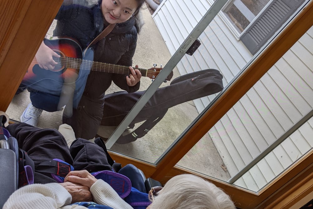 Staff serenades a resident through a window at Ramsey Woods in Cudahy, Wisconsin.
