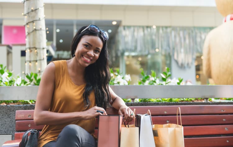 Woman sitting on a bench with her shopping bags near Sage Luxury Apartment Homes in Phoenix, Arizona