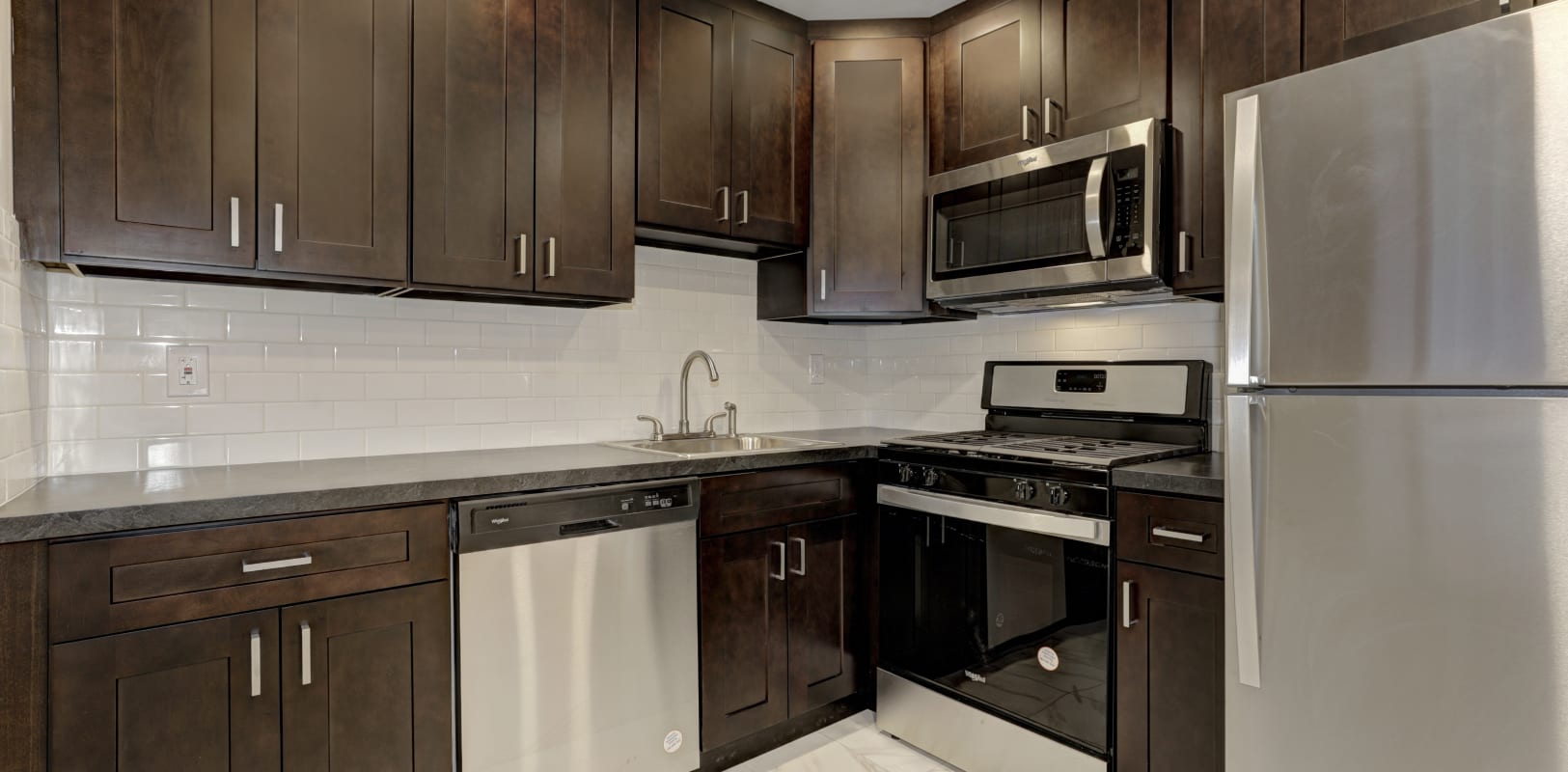 Kitchen with dark wood cabinets and stainless steel appliances at Bridle Path Apartments in Bethlehem, Pennsylvania