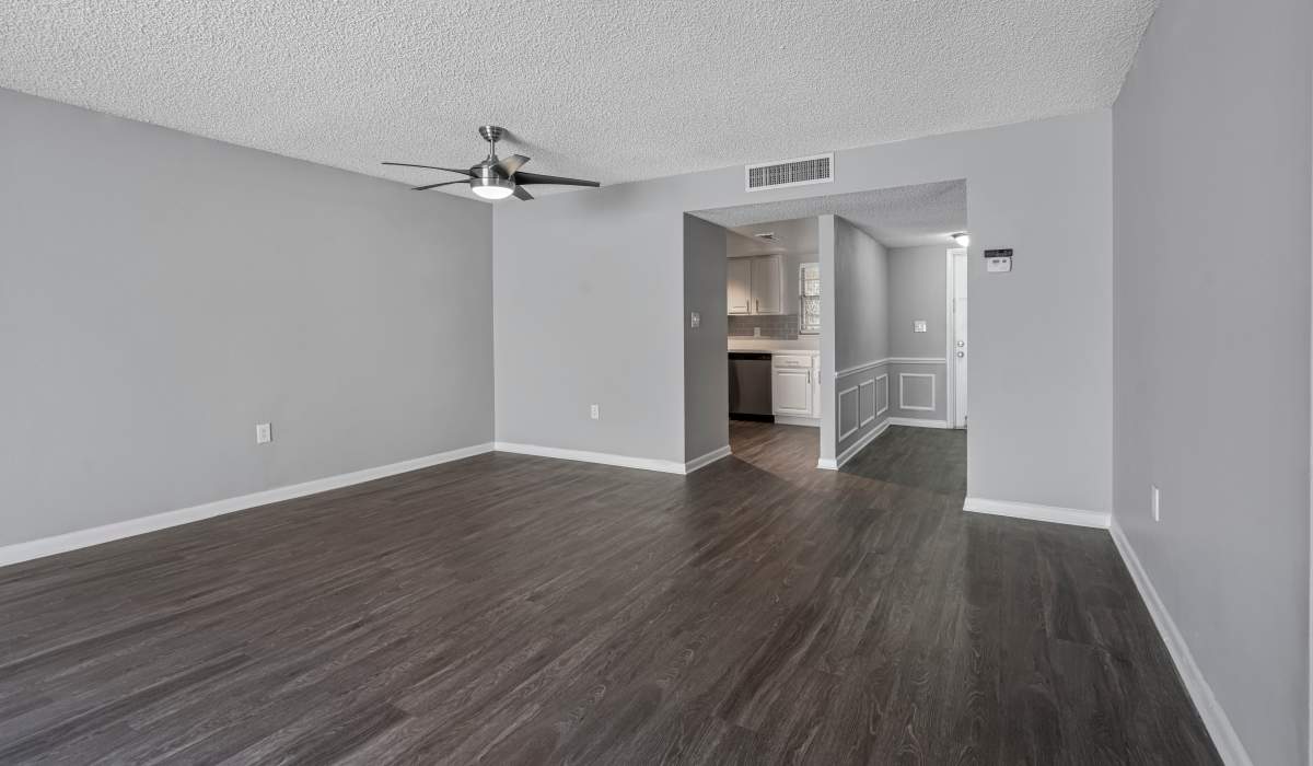 Spacious apartment living area with wood-style flooring and neutral walls in Marbella Park in Orlando, Florida