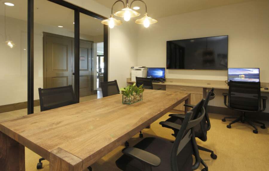Modern conference room with wooden table and sleek tech setup at Messina Luxury Apartments in New Smyrna Beach, Florida