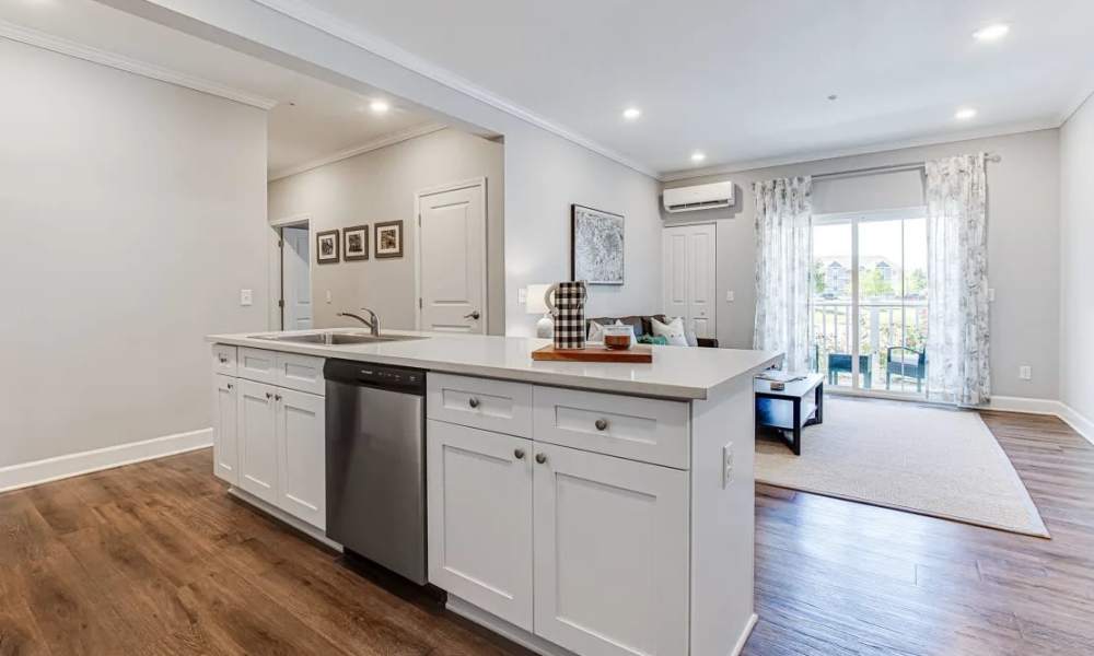 Open layout kitchen with granite countertops, stainless steel appliances, and wood-style flooring leading to a balcony at Everett at Port Wentworth in Port Wentworth, Georgia