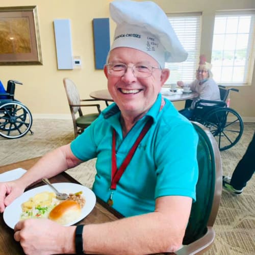 Resident with a large plate of food wearing a chefs hat at The Oxford Grand Assisted Living & Memory Care in McKinney, Texas