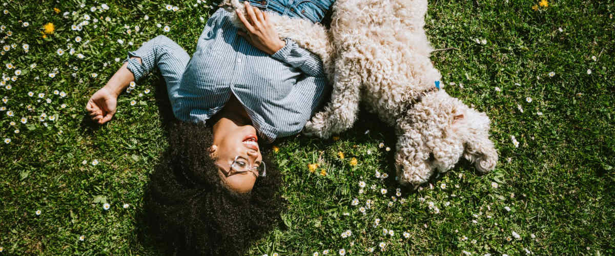 Happy lady laying on the grass with her happy dog at Champions Vue Apartments in Davenport, Florida