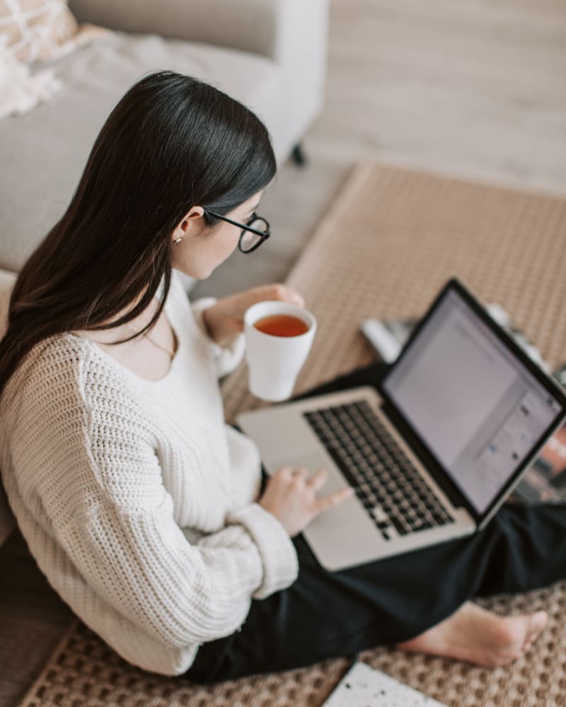 resident working on a laptop sitting on her floor at Trinity Way in Fremont, California