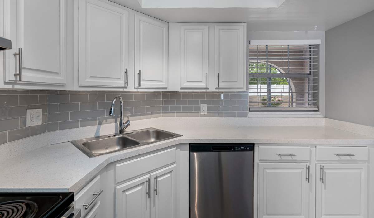 Bright kitchen featuring white cabinetry, double sink, and dishwasher in Marbella Park in Orlando, Florida