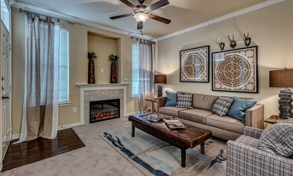 Living room with built-in shelving, wall-to-wall carpeting and a ceiling fan in a model home at Chateau Mirage Apartment Homes in Lafayette, Louisiana