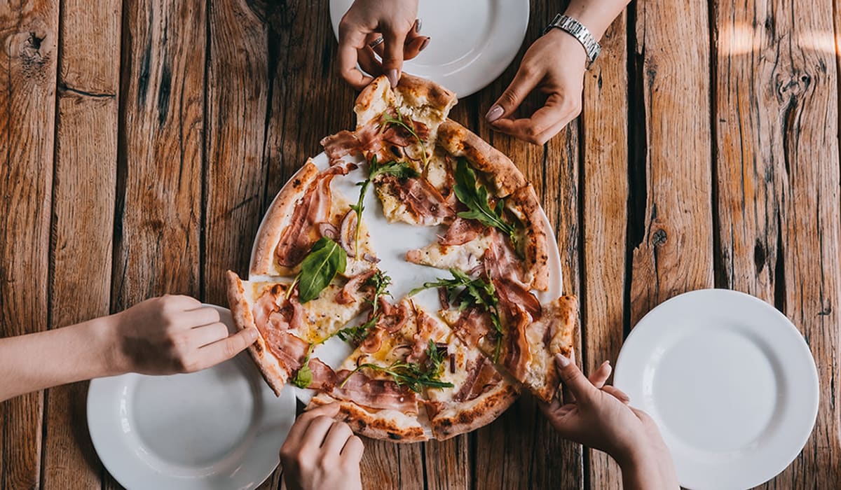 Hands grabbing slices of pizza near Barrett Apartment Homes in Garland, Texas